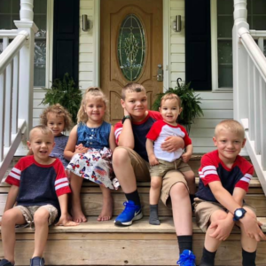 6 young kids sitting on front porch wooden stairs